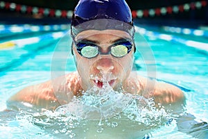 Driven to improve his lap time. Cropped view of a determined male swimmer swimming laps.