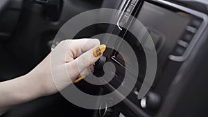 The driver adjusting the volume of a radio inside a car. Action. Close up of a woman hand with yellow manicure turning