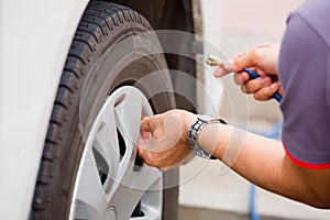 Driver checking air pressure and filling air in the tires close up