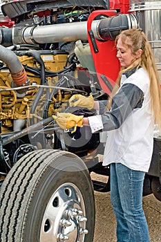 Driver checking oil and pre-trip inspection on a big truck.