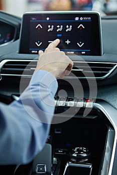 The driver controls the air conditioning in a modern electric car photo