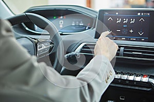 The driver controls the air conditioning in a modern electric car photo