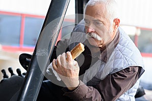 Driver eating bread while driving classic tractor