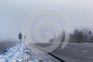 Driver of almost empty grey foggy misty rainy highway intercity road with low poor visibility on cold spring autumn morning.