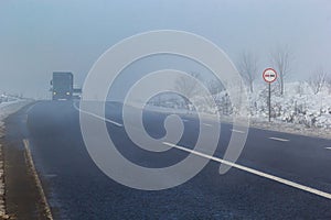 Driver of almost empty grey foggy misty rainy highway intercity road with low poor visibility on cold spring autumn morning.