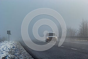 Driver of almost empty grey foggy misty rainy highway intercity road with low poor visibility on cold spring autumn morning.