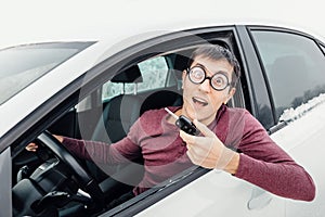 Driver in eye glasses holding the car key and smiling to the camera. Concept of a newbie driver and insurance