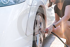 Driver filling air into a car tire, tire inflation