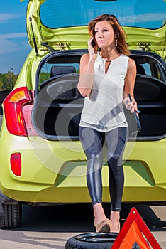 Driver girl calling mechanic standing near the car