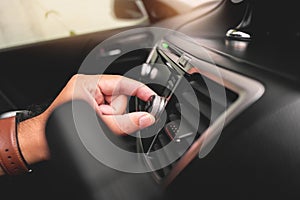 The driver hand adjusts the volume button of car radio.