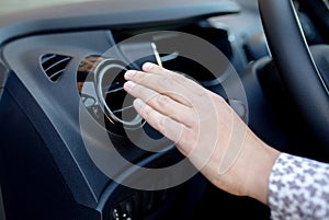 Driver hand on air ventilation grille with power regulator, modern car interior detail