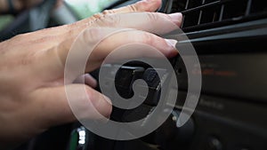 Driver hand tuning air ventilation grille on black plastic retro car dashboard