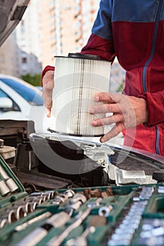 Driver hands inserting air cartridge inside airbox of car engine, close up view