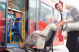 Conductor ayúdamos lámina el autobús a través de silla de ruedas 