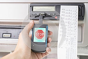 Driver holding a digital tachograph reader with big red stop mark on the screen. Tachograph download. Control.