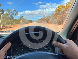 Driver holding steering wheel while driving an off road car land vehicle on a long off road