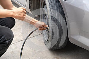 Driver man hand inflating car tire, check to raise the pressure, compressor and maintain wheels inflate