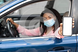 Driver in mask using showing smartphone with empty screen
