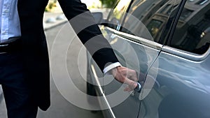 Driver opening car door to young respectable oligarch, professional chauffeur