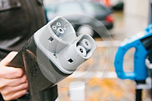 The driver picks up a cable to charge the electric vehicle. A modern and eco-friendly mode of transport that has spread