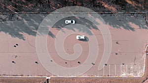 Driver practicing to drive car at abandoned parking lot, aerial drone top view. Car is in abandoned parking lot