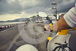 Driver riding motorcycle on an asphalt empty road near sea.