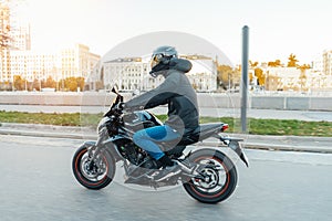 Driver riding motorcycle on empty road in beautiful autumn city.