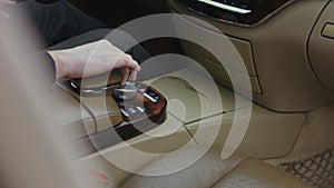 The driver's finger presses the hazard warning button on the shiny dashboard of the car. The button flashes red