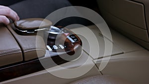 The driver`s finger presses the hazard warning button on the shiny dashboard of the car. The button flashes red. Luxury
