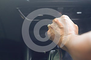Driver`s hand holding automatic gear stick to shift the gear while sitting in the car driver`s seat and driving luxurious super