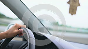 Driver s hand on steering wheel against background of dashboard and windshield