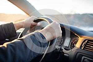 Driver`s hand on steering wheel of car in cabin.