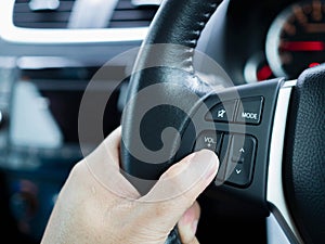 Driver`s hands press volume button on a steering wheel