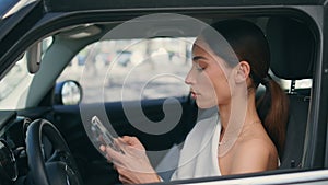 Driver smartphone sitting car wheel looking window closeup. Chic woman scrolling