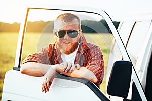 Driver in sunglasses stands near his car