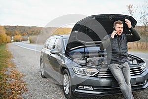 driver trying to figure out how to fix broken down car with red triangle to warn other road users