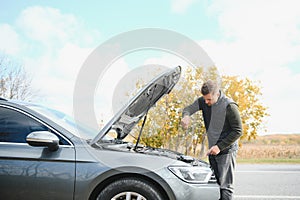 driver trying to figure out how to fix broken down car with red triangle to warn other road users