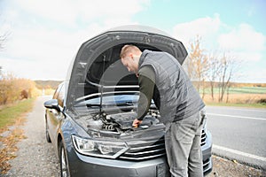 driver trying to figure out how to fix broken down car with red triangle to warn other road users