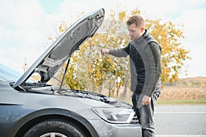 driver trying to figure out how to fix broken down car with red triangle to warn other road users