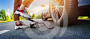 Driver using a foot pump to inflate a tire