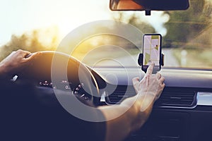 Driver using GPS navigation in mobile phone while driving car photo