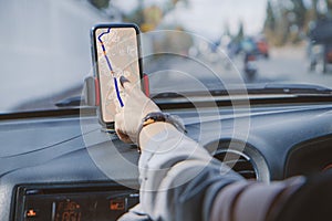 Driver using GPS navigation in mobile phone while driving car. Woman driving while using the mapping app on his smartphone to find