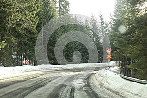 Driver view on sharp road curve, partially covered with snow in
