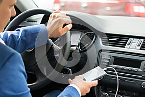 The driver at the wheel of the car turns on the music from the phone