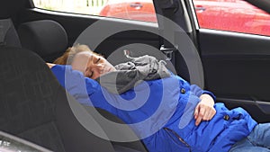 The driver of the woman fell asleep on the driver`s seat on the side of the road. Waiting in the car.