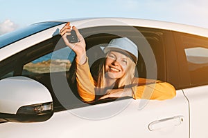 Driver woman traveling by rental car showing keys in open window. Road trip vacations