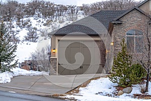 Driveway and garage entrance of home against snowy hill landscape in winter