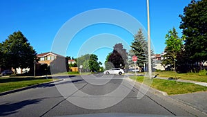 Driving Around a Bend of Residential City Road With Lush Trees During Summer Day.  Driver Point of View POV Turning