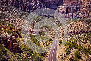 Driving through Badlands - Zion National Park - Utah USA - two land highway through shrub and trees and towering rocky cliffs