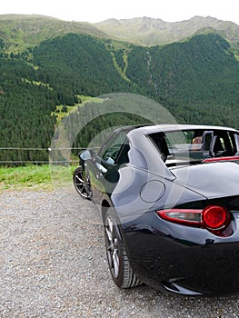 Driving a black cabriolet car in austrian Alps